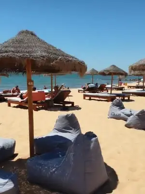 a beach with umbrellas and people laying on the sand at Lindo apartamento junto à praia e à Marina de Vilamoura com Piscina e Wi-Fi in Quarteira