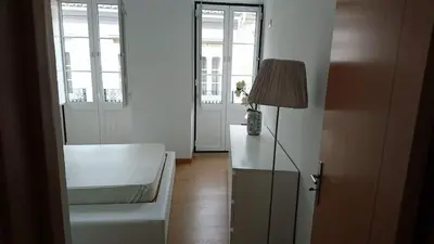a living room with a white chair and a lamp at Faro City Center Apartment I in Faro