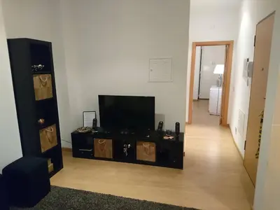 a living room with a flat screen tv and a hallway at Faro City Center Apartment I in Faro