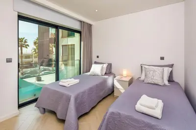two beds in a room with a large window at Apartamento Porlamar in Quarteira