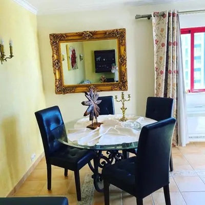 a dining room with a table and chairs and a mirror at Castelo I in Quarteira