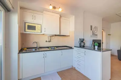 a kitchen with white cabinets and a microwave at Vilamoura Cosy 2 with Pool by Homing in Vilamoura