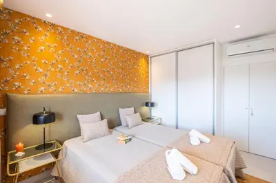 two beds in a bedroom with a orange wall at Apartment Melbourne 1 by Algarve Vacation in Albufeira