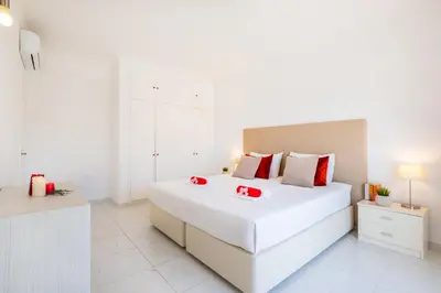 a white bedroom with a large white bed with red accents at Villa Perola by Algarve Vacation in Albufeira