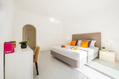 a white bedroom with a large bed with orange pillows at Villa Perola by Algarve Vacation in Albufeira