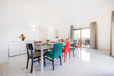a dining room with a table and colorful chairs at Villa Perola by Algarve Vacation in Albufeira