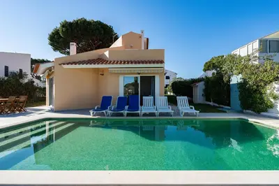 a swimming pool with blue chairs and a house at Villa Mianas by SAPvillas in Vilamoura
