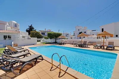 a swimming pool with chaises and chairs next to a villa at Villux - Vila Enar-6 quartos, ideal para familias in Albufeira