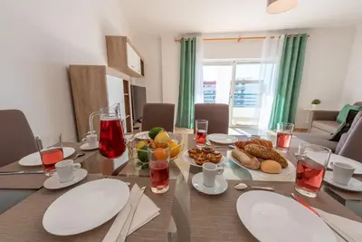 a dining room table with plates and food on it at Apartamento Monarquia - T3 Quarteira in Quarteira