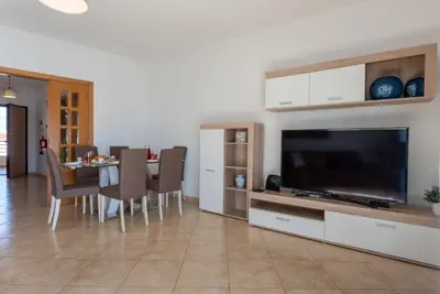 a living room with a dining table and a flat screen tv at Apartamento Monarquia - T3 Quarteira in Quarteira