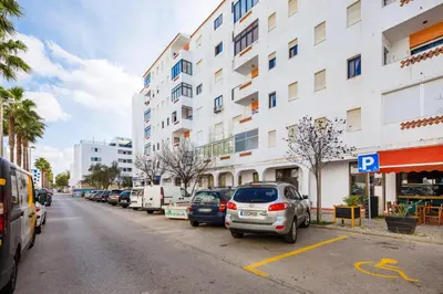 a parking lot with cars parked in front of a building at Apartamento Vista Mar T2 in Quarteira