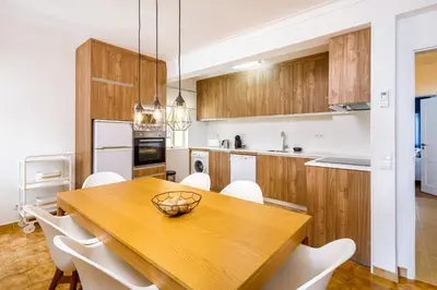 a kitchen with a wooden table and white appliances at Apartamento Vista Mar T2 in Quarteira