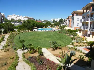 a large lawn in front of a building with a swimming pool at Luxurious first floor apartment with balconies overlooking pool and gardens. in Albufeira