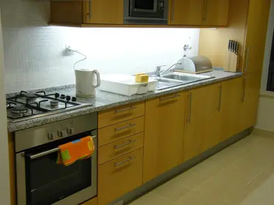 a kitchen with wooden cabinets and a table with chairs at Luxurious first floor apartment with balconies overlooking pool and gardens. in Albufeira