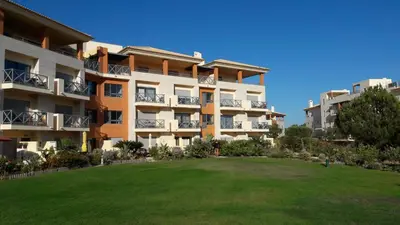 a bedroom with a bed and a mirror and a chair at Luxurious first floor apartment with balconies overlooking pool and gardens. in Albufeira