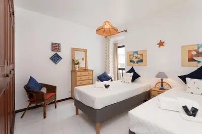 a bedroom with two beds and a chair at Centralgarve - Great, Bright 2-bedroom Flat in the Center of Vilamoura -Topázio in Vilamoura
