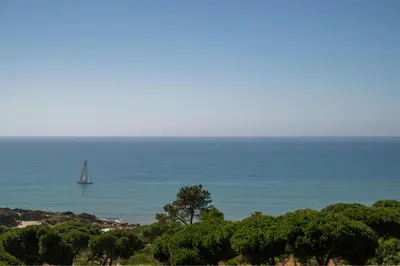 a boat in the ocean with a sail boat at W Residences Algarve in Albufeira