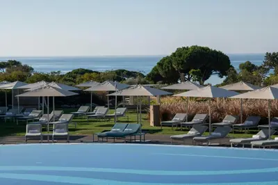 a group of chairs and umbrellas next to a pool at W Residences Algarve in Albufeira