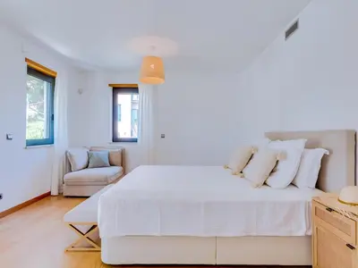 a white bedroom with a white bed and a chair at Vale do lobo, 'Golf by the Pool' 2 bedroom apartment in Vale do Lobo