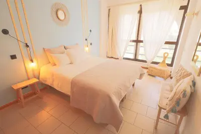 a bedroom with a bed and a window and a chair at Apartamentos Ninho das Gaivotas in Albufeira