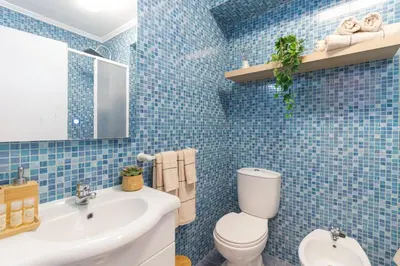 a blue tiled bathroom with a toilet and a sink at Sea & Sun OldTown in Albufeira