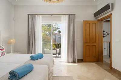 a bedroom with two beds and a door to a balcony at Villa Flamingo - Quinta do Mar in Almancil