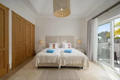 a bedroom with a large bed with blue pillows at Villa Flamingo - Quinta do Mar in Almancil