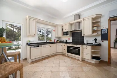 a kitchen with white cabinets and black counter tops at Villa Flamingo - Quinta do Mar in Almancil