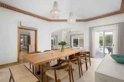 a dining room with a wooden table and chairs at Villa Flamingo - Quinta do Mar in Almancil