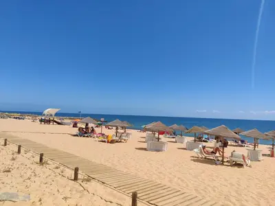 a group of people sitting on a beach with umbrellas at Go4Portugal - Lagoa - Apartment 3 min from beach with airco and balcony in Quarteira