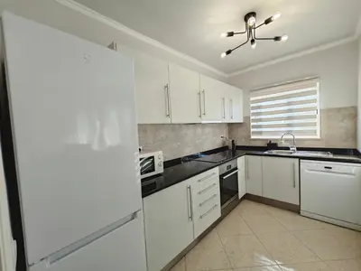 a kitchen with white cabinets and a ceiling fan at Alojamento King´s Village in Albufeira