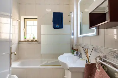 a bathroom with a white tub and a sink and a bath tubermott at Pedra dos Bicos by Intiholidays in Albufeira