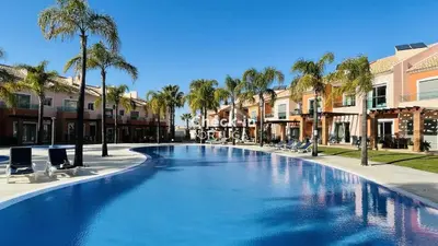 a large swimming pool with chairs and palm trees at Santa Maria C by Check-in Portugal in Albufeira