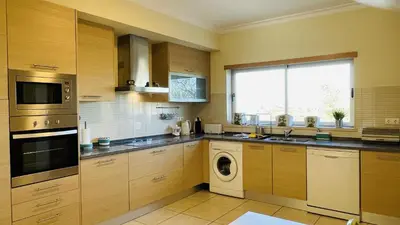 a kitchen with wooden cabinets and a washer and dryer at Santa Maria C by Check-in Portugal in Albufeira