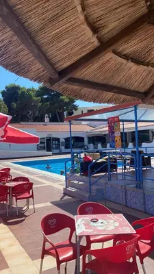 a patio with tables and chairs and a swimming pool at Albufeira Garden in Albufeira
