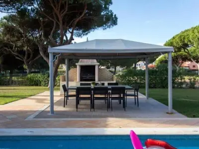 a pavilion with a table and chairs next to a pool at Vilamoura Golf Mansion by Stay ici Algarve Holiday Rental in Quarteira