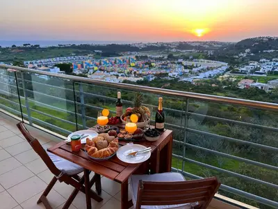a table with food and wine on a balcony with the sunset at AlbufeiraOrada Gem by Be Cherish in Albufeira