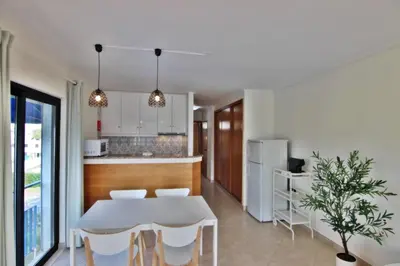 a kitchen and dining room with a white table and chairs at Pé do Lago Apartment - Condominium - Pool in Quarteira