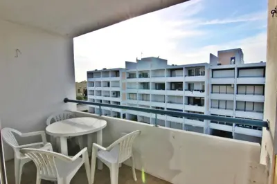 a balcony with chairs and a table and a building at Pé do Lago Apartment - Condominium - Pool in Quarteira