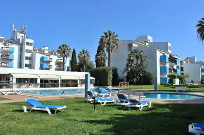 a group of lounge chairs next to a swimming pool at Lago Azul Apartment I in Quarteira