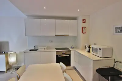 a small kitchen with white cabinets and a microwave at Lago Azul Apartment I in Quarteira