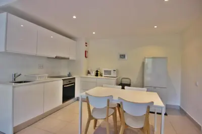 a kitchen with white cabinets and a table and chairs at Lago Azul Apartment I in Quarteira