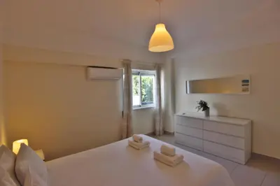 a bedroom with a white bed and a window at Lago Azul Apartment I in Quarteira