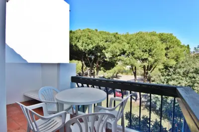 a balcony with a table and chairs and trees at Lago Azul Apartment I in Quarteira