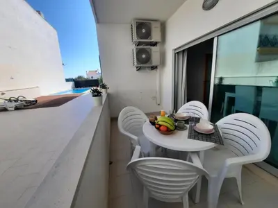 a small white table and chairs on a balcony at Casa Mandala, T1 com piscina in Albufeira