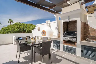 a patio with a table and chairs and a grill at Casa Ch'i - Vale de Lobo in Almancil