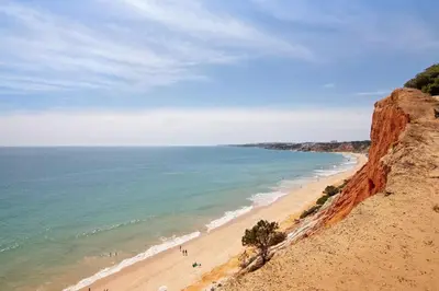 a beach with people walking on it next to the ocean at Apartamento Medusa by Sunnyway in Olhos de Água