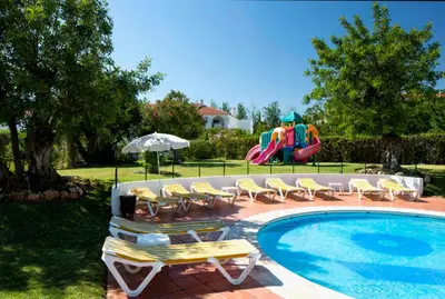 a pool with chairs and a playground with a slide at Apartamento Albufeira Prestige by Sunnyway in Albufeira