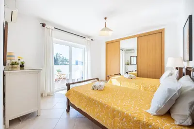 a bedroom with two beds and a large window at Villa dos Netos in Albufeira