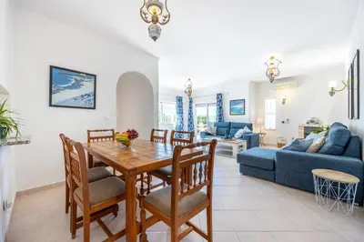 a dining room and living room with a table and chairs at Villa dos Netos in Albufeira